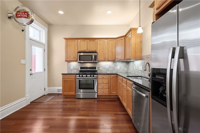 kitchen with pendant lighting, stainless steel appliances, dark wood-type flooring, and sink