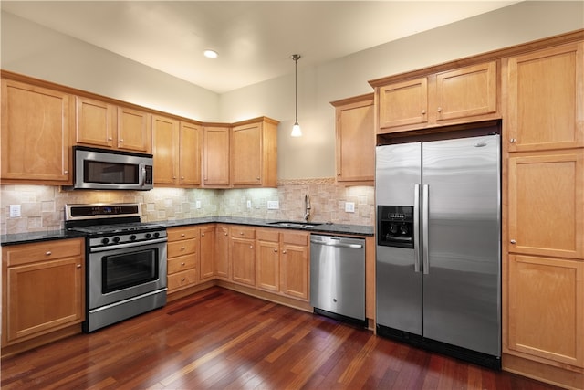 kitchen with decorative backsplash, appliances with stainless steel finishes, dark wood-type flooring, sink, and pendant lighting