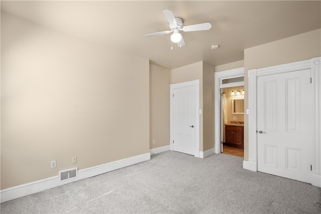 unfurnished bedroom featuring ensuite bath, ceiling fan, and light colored carpet