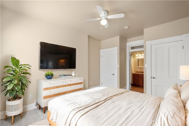 bedroom with connected bathroom, light carpet, and ceiling fan