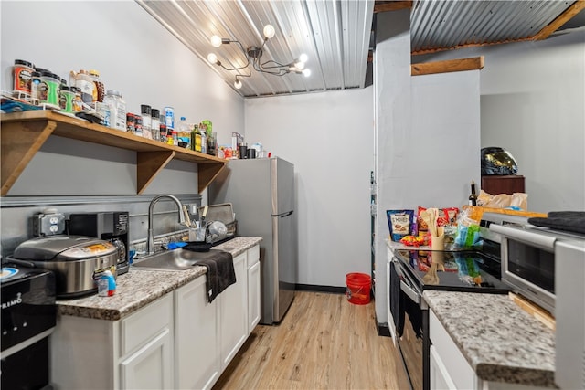 kitchen with white cabinetry, light stone counters, stainless steel appliances, light hardwood / wood-style flooring, and sink