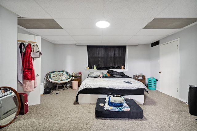 carpeted bedroom featuring a drop ceiling