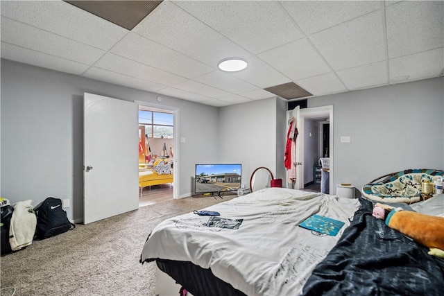 bedroom featuring a drop ceiling and carpet floors