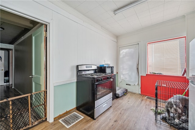 kitchen with gas stove, ornamental molding, and light wood-type flooring