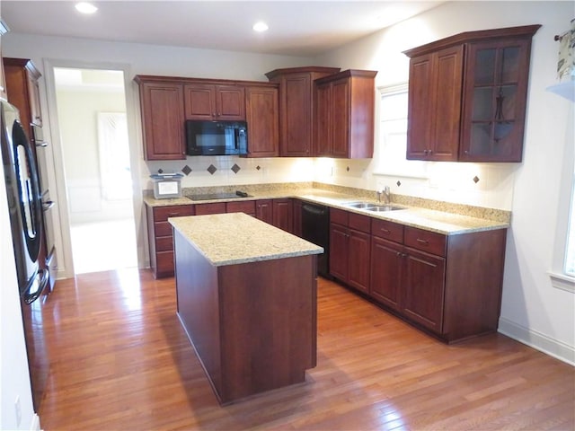 kitchen featuring light stone countertops, sink, light hardwood / wood-style floors, a kitchen island, and black appliances