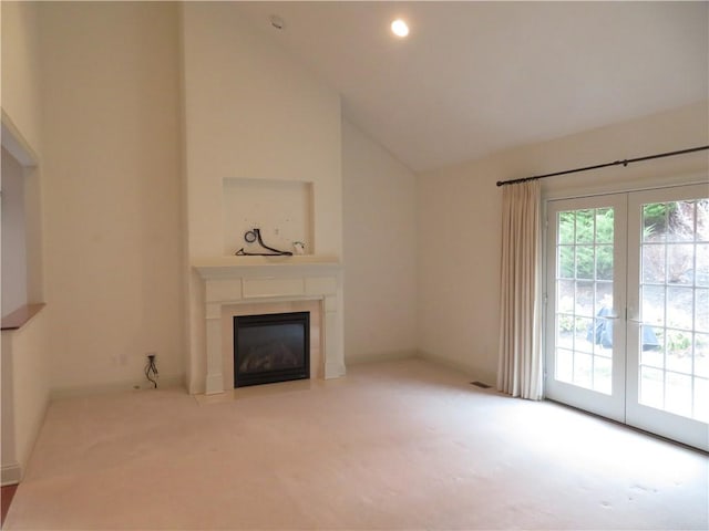 unfurnished living room featuring light colored carpet, high vaulted ceiling, and french doors