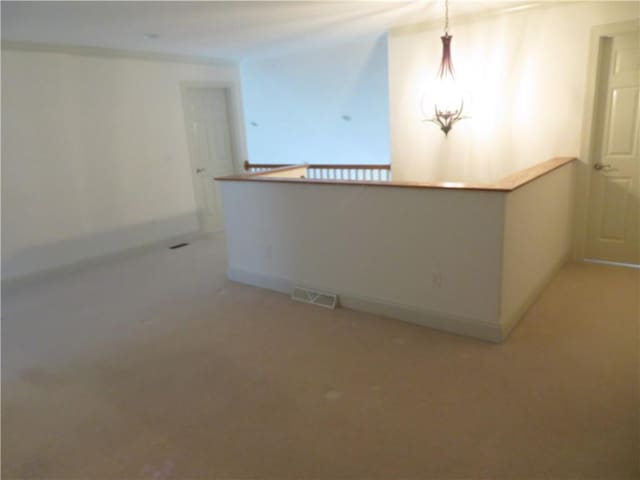 carpeted spare room with a notable chandelier