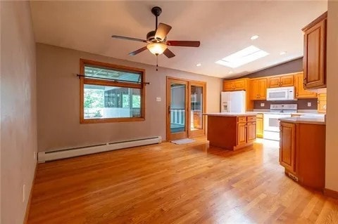 kitchen with vaulted ceiling with skylight, white appliances, a kitchen island, a baseboard radiator, and light wood-type flooring