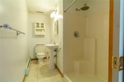 bathroom with walk in shower, toilet, and baseboard heating