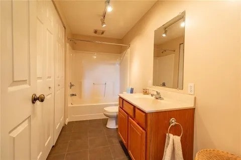 full bathroom with shower / bath combination, vanity, tile patterned flooring, track lighting, and toilet