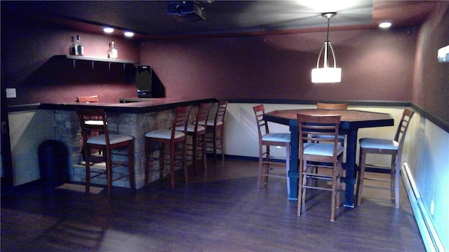 bar with wood-type flooring, baseboard heating, and hanging light fixtures