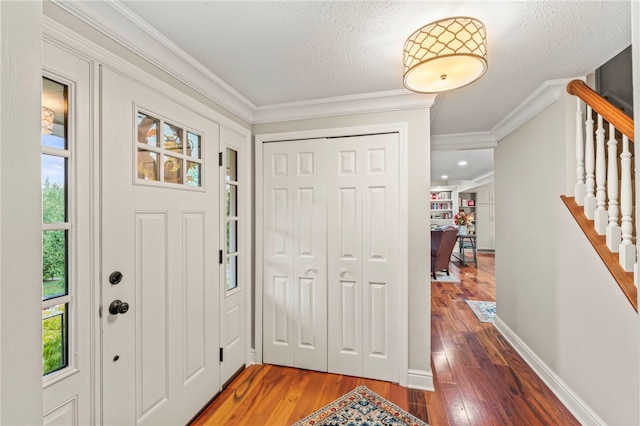 foyer featuring a textured ceiling, ornamental molding, and hardwood / wood-style flooring