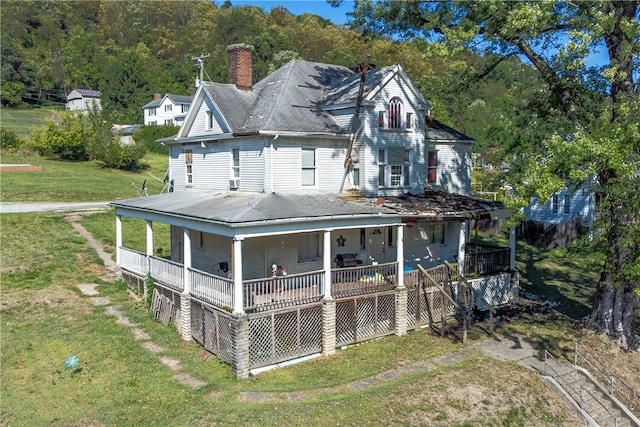 back of property featuring a lawn and covered porch