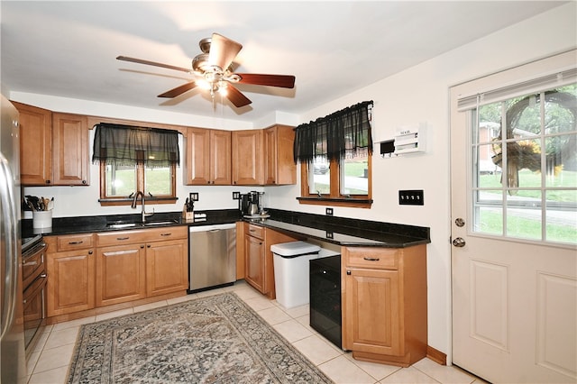 kitchen with dark stone countertops, light tile patterned floors, sink, and stainless steel dishwasher