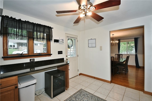 kitchen with black refrigerator, ceiling fan with notable chandelier, and light tile patterned floors