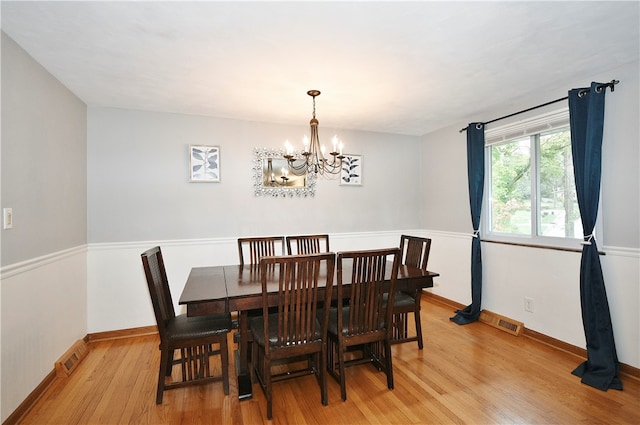 dining area with light hardwood / wood-style flooring and a notable chandelier