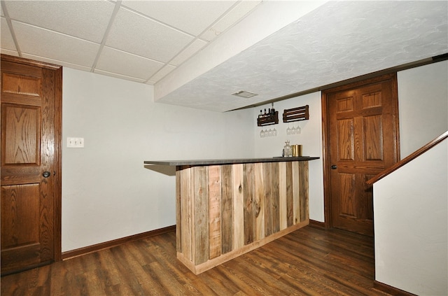 bar with dark hardwood / wood-style floors and a paneled ceiling