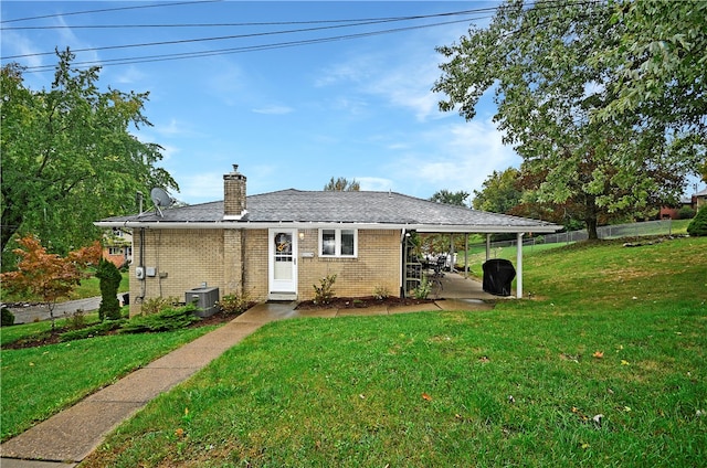 view of front of house with central AC unit, a front lawn, and a carport