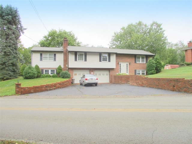 raised ranch featuring a garage and a front lawn