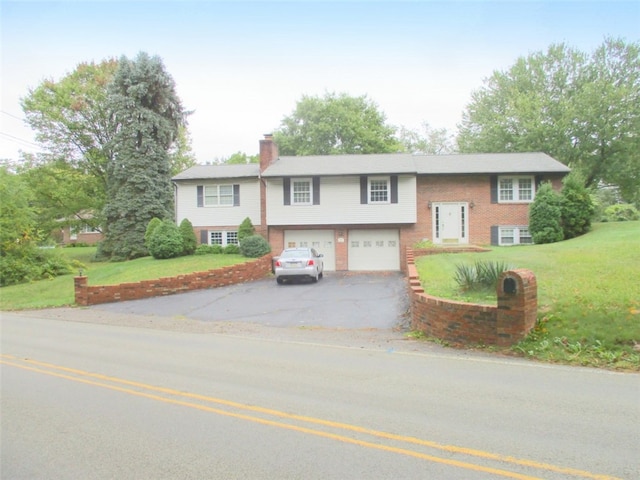 raised ranch featuring a front yard and a garage