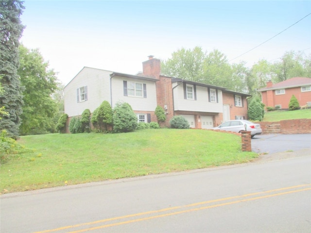 raised ranch with a garage and a front lawn