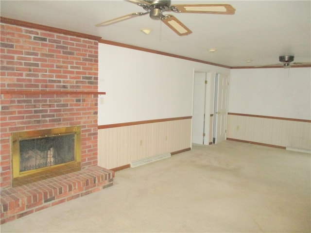 unfurnished living room with light carpet, ceiling fan, a fireplace, and crown molding