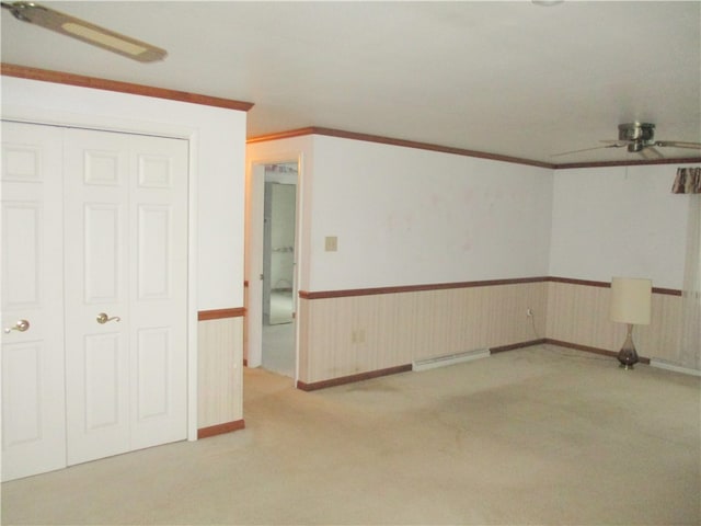 spare room with ornamental molding, a baseboard heating unit, ceiling fan, and light colored carpet