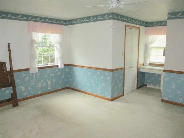 unfurnished room featuring carpet flooring, ceiling fan, and a wealth of natural light