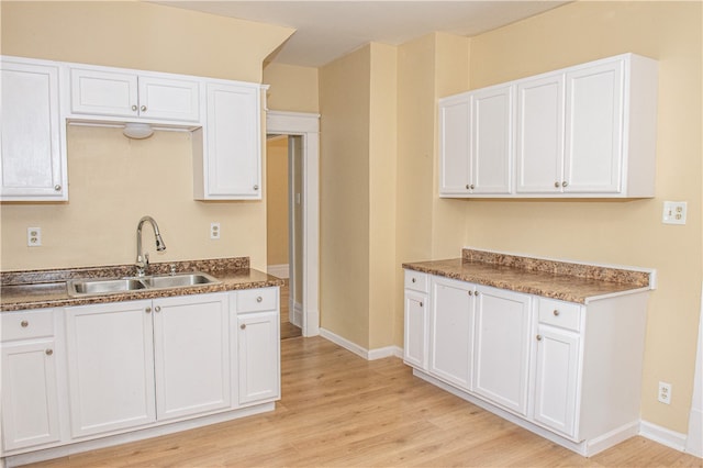 kitchen with light hardwood / wood-style floors, sink, and white cabinetry