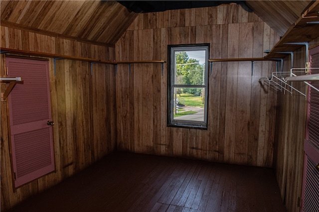 additional living space with wooden walls, vaulted ceiling, and dark hardwood / wood-style flooring