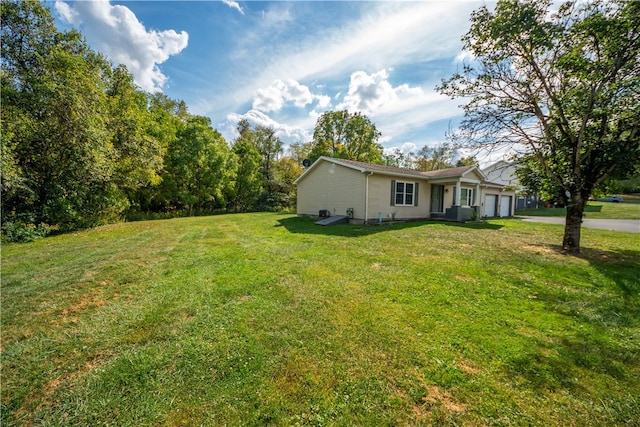 view of yard featuring central AC unit and a garage