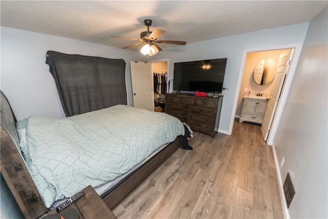 bedroom featuring a closet, ensuite bathroom, hardwood / wood-style floors, a spacious closet, and ceiling fan