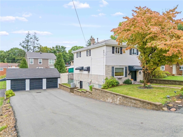 view of front of property featuring a garage, a front lawn, and an outbuilding