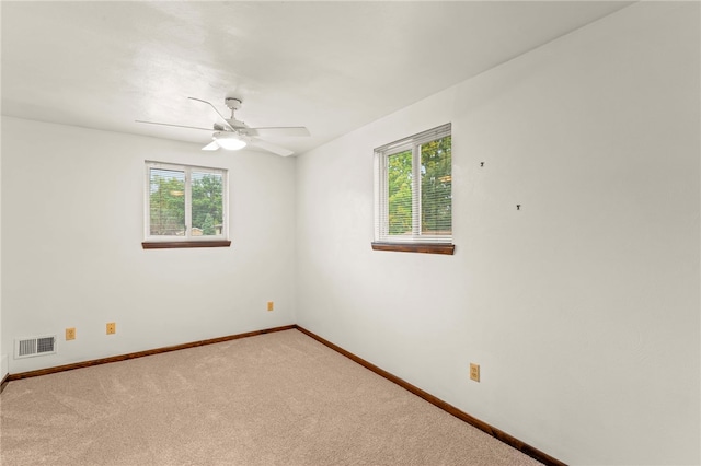 carpeted spare room featuring ceiling fan and a wealth of natural light