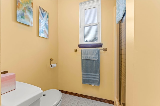 bathroom with tile patterned floors, a shower with shower door, and toilet