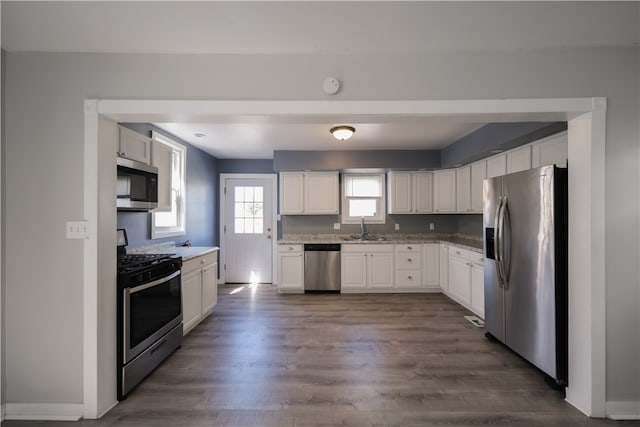 kitchen featuring appliances with stainless steel finishes, decorative backsplash, white cabinetry, dark hardwood / wood-style flooring, and sink