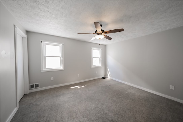 unfurnished room featuring ceiling fan, a textured ceiling, carpet flooring, and a wealth of natural light