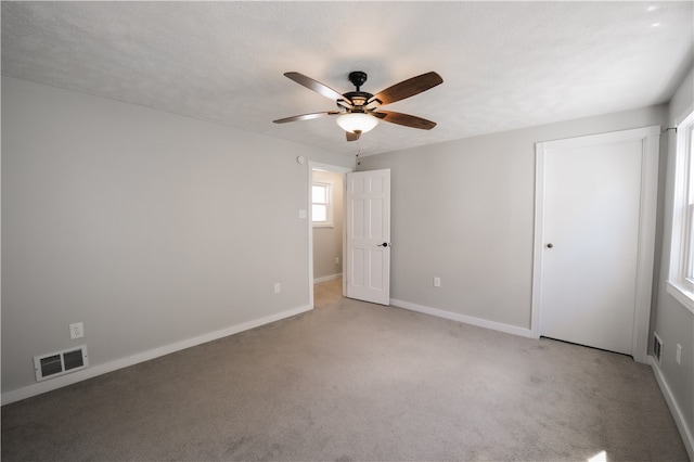 unfurnished bedroom with a textured ceiling, ceiling fan, and light colored carpet