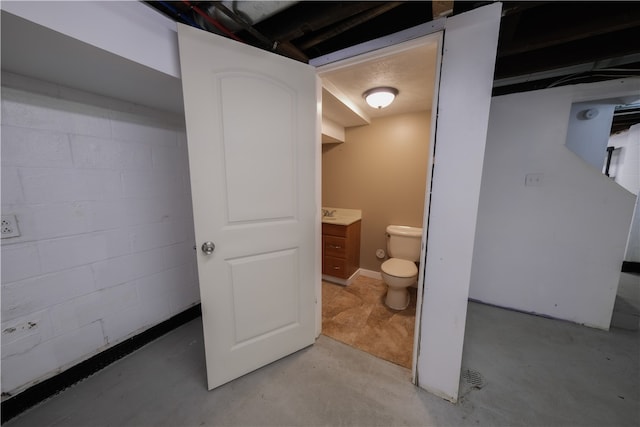 bathroom with concrete flooring, vanity, and toilet