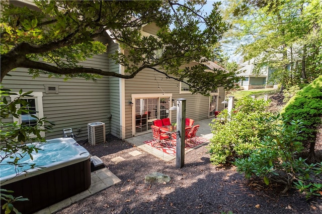 rear view of property with central air condition unit, a patio, and a hot tub