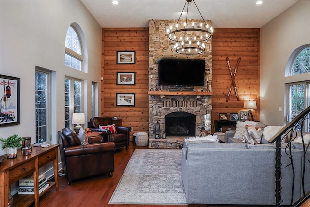 living room featuring an inviting chandelier, a fireplace, plenty of natural light, and dark wood-type flooring