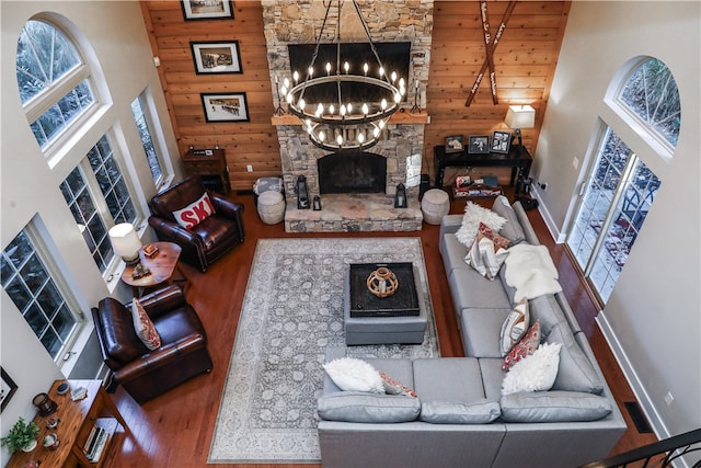 living room with a high ceiling, wooden walls, plenty of natural light, and wood-type flooring