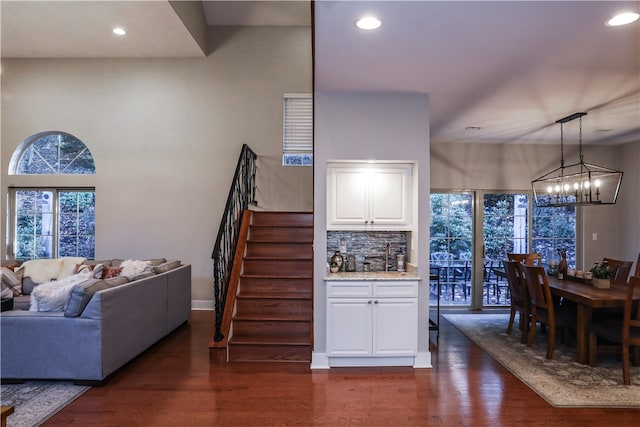 interior space featuring light stone counters, white cabinets, decorative light fixtures, backsplash, and dark hardwood / wood-style floors