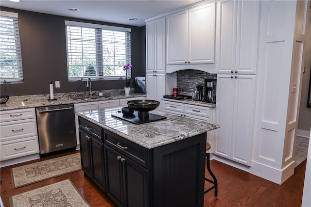 kitchen with dark hardwood / wood-style flooring, sink, stainless steel dishwasher, a center island, and white cabinetry