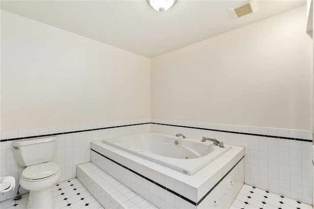 bathroom with tiled tub, tile walls, toilet, and tile patterned floors