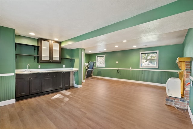 kitchen with light hardwood / wood-style flooring, dark brown cabinets, a textured ceiling, and sink