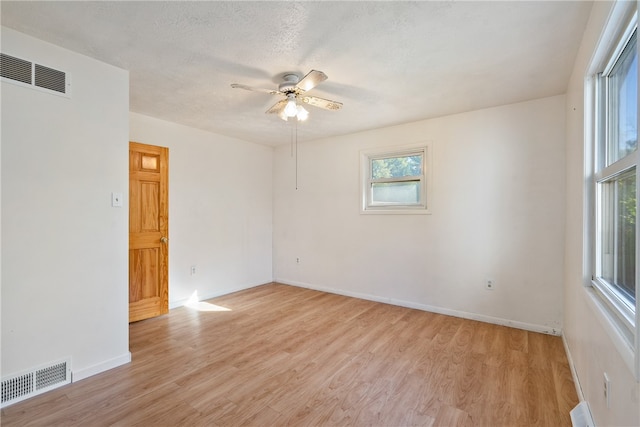 unfurnished room featuring a wealth of natural light, light hardwood / wood-style floors, and a textured ceiling