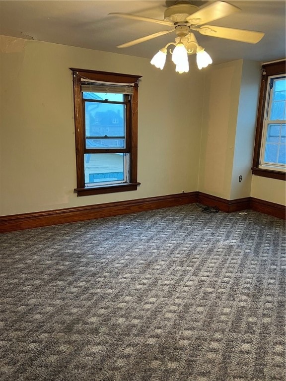 empty room with ceiling fan and dark carpet