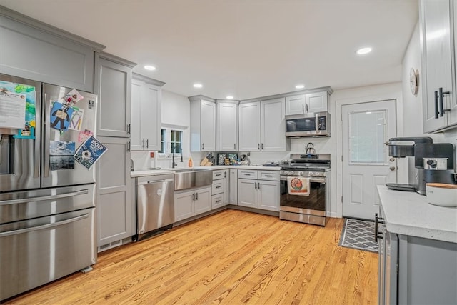 kitchen featuring gray cabinetry, appliances with stainless steel finishes, sink, and light hardwood / wood-style flooring