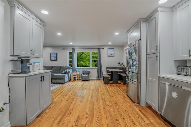 kitchen with appliances with stainless steel finishes, gray cabinetry, and light hardwood / wood-style floors